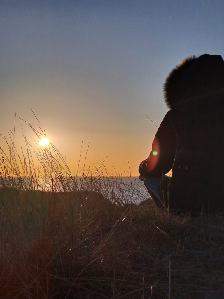 Katharina Jacob sitzt in der Natur bei Sonnenuntergang – in sich gekehrt und ruhig